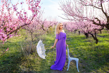 Wall Mural - beautiful woman with umbrella on a Sunny day in the blossoming garden, lovely spring day for a walk, peach blossom or Sakura