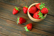 View above of handful of strawberry crop on a wooden background