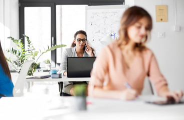 business, technology, communication and people concept - happy businesswoman calling on smartphone at office