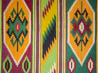 Close up of geometric patterned carpet. Hand woven rug with red, yellow, blue and other colors. Hand woven carpet with abstract design. Colorful carpet. Textile background. Abstract background.