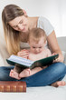© Kyrylo Ryzhov - Cute 1 year old baby boy sitting on mothers lap and reading big old book