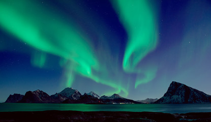 northern lights, aurora borealis shining green in night starry sky at winter lofoten islands, norway