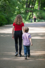 Brothers walking in spring sunny park. Back view.