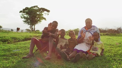 family sitting on the grass and waving hands