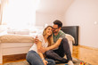 © Nebojsa - Happy young man hugging his girlfriend while sitting on the floor in bedroom