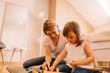 © Nebojsa - Mother and daughter playing with toys together on a floor
