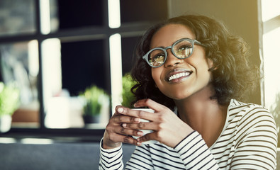 Wall Mural - Young African woman smiling and enjoying coffee in a cafe