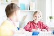 © pressmaster - Cute schoolgirl with pencil looking at her classmate during topic discussion at lesson