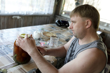 Man opening jar with pickled tomatoes