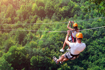 zipline is an exciting adventure activity. man and woman hanging on a rope-way. tourists ride on the