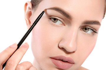 Poster - Beautiful woman with perfect eyebrows applying makeup on light background