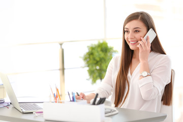 Young woman talking on phone at workplace