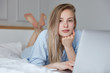 © WHstudio Leushin N - Picture of beautiful young Caucasian female in fashionable pajamas browses internet on laptop computer, connected to wireless internet, makes shopping online, lies on undone bed, feels relaxed