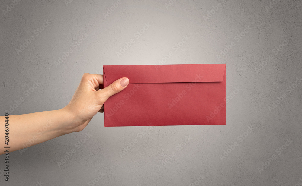 Female hand holding coloured and white envelope with empty wall ...