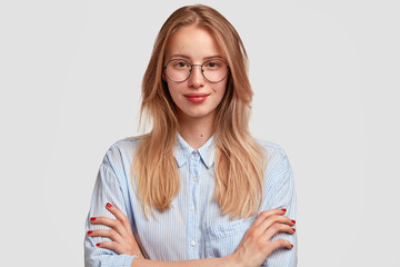 Wall Mural - Studio shot of good looking intelligent female professor, doesn`t have much experience, wears big round spectacles, isolated over white background. Caucasian college student recieves good proposal