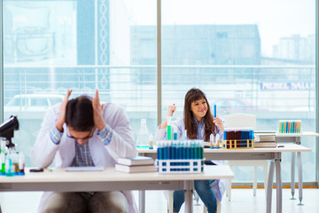 two chemists working in lab experimenting