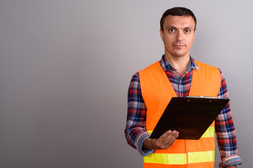 Man construction worker holding clipboard against gray backgroun