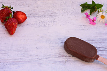 Classic popsicle vanilla ice cream covered whit chocolate and fresh red strawberries at light wooden background 