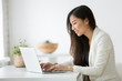 © fizkes - Smiling young asian businesswoman using computer at home office workplace, happy korean employee working on laptop, attractive japanese or chinese woman student studying communicating online with pc