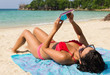 © Josu Ozkaritz - Girl in pink bikini lying on a blue sarong holding a tablet in Secret Beach, Koh Pha Ngan, Thailand
