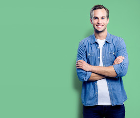 Wall Mural - Portrait of young man standing in crossed arms pose