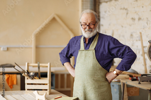 Fotomural cheerful senior citizen is ready to work in the workshop