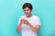 © makistock - Young man texting message on smart phone isolated on blue background