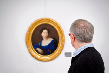 Visitor looking painting in art gallery. Art critic assesses