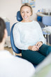 © Seventyfour - Beautiful casual woman on seat in dentist cabinet talking to doctor and smiling happily.