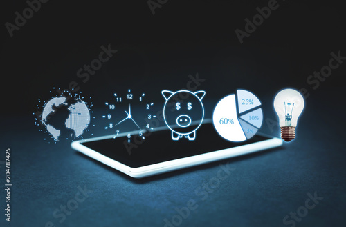 Fotografía Globe, clock, piggy bank, pie graph and light bulb on digital tablet