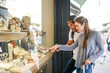 © W PRODUCTION - cheerful young couple looking at jewelry shop window in summer