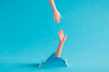 Two plastic hands on pastel blue background support abstract concept.