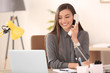 © New Africa - Young woman talking on phone at workplace