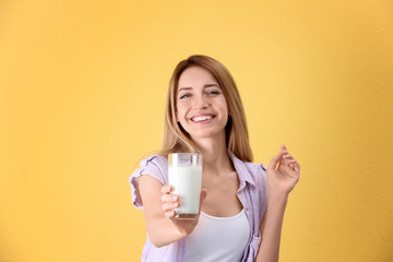 Canvas Print - Beautiful young woman drinking milk on color background