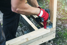 wood shed construction - man screwing corner joint brace