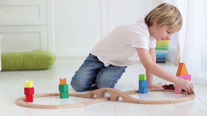 Wall Mural - young happy kid playing with toy railway and train at home