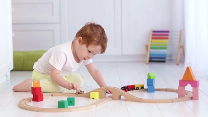 Wall Mural - cute toddler boy playing the toy train and railroad at home