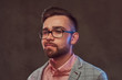 © Fxquadro - Close-up portrait of a confident stylish bearded man with hairstyle and glasses in a gray suit and pink shirt, posing in a studio.