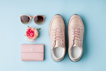 Flat lay pink feminine accessories on blue background.