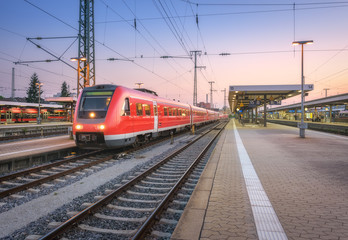 Wall Mural - high speed red train on the railway station at sunset. nuremberg, germany. colorful urban landscape.