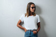 © Alex from the Rock - Stylish woman in white blank t-shirt wearing glasses, grunge wall, horizontal studio portrait
