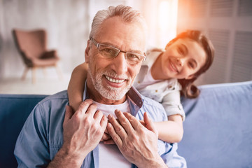 The happy girl hugs a grandfather on the sofa