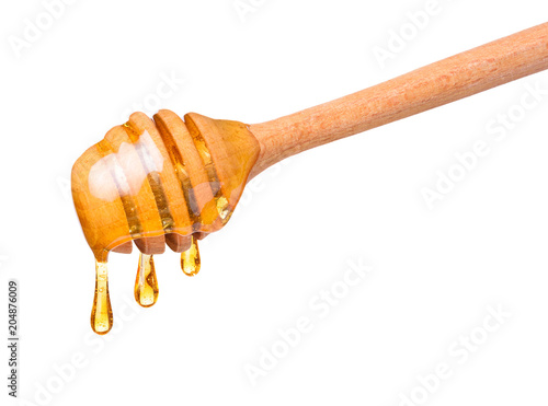 Photographie Honey drops dripping from wooden dipper spoon isolated on white background