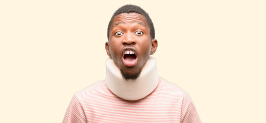 Wall Mural - Injured african black man wearing neck brace stressful, terrified in panic, shouting exasperated and frustrated. Unpleasant gesture. Annoying work drives me crazy