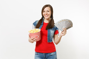 Portrait of young smiling attractive woman in casual clothes watching movie film, holding bucket of popcorn and bundle of dollars, cash money isolated on white background. Emotions in cinema concept.