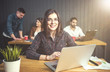 © proimagecontent - Portrait of brunette girl wears eyeglasses using silver laptop computer before office colleagues, indoor shot of working atmosphere