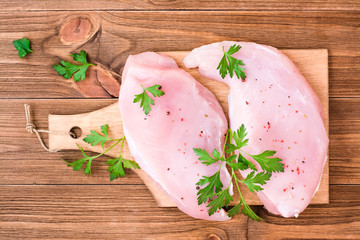 Raw turkey fillet in spices and herbs on a cutting board on a wooden table. Top view