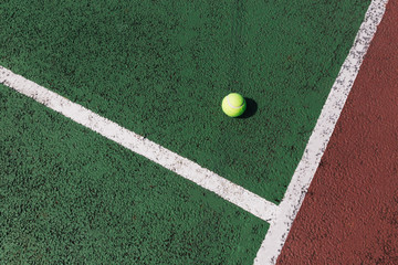 Yellow tennis ball on green tennis court