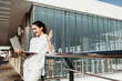© Yakobchuk Olena - Content woman standing on balcony with notebook and waving hand to screen. Copy space in right side