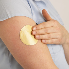 young woman applying flesh coloured nicotine patch to arm